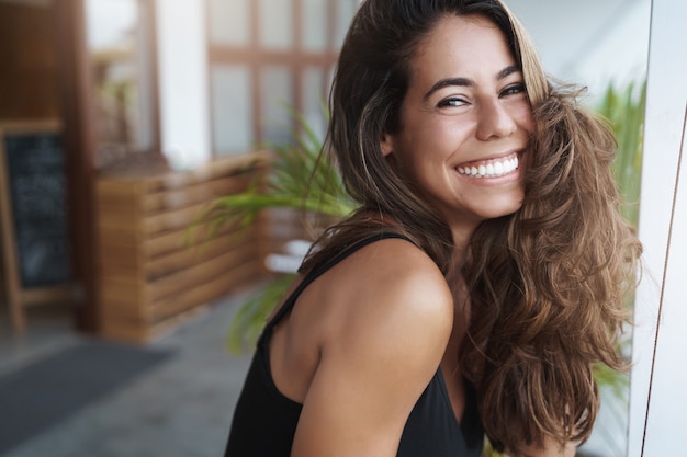 Enthousiaste belle jeune femme bronzée se pencher sur la terrasse et regarder joyeusement