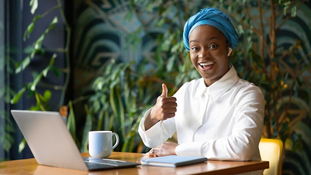 Enthousiaste dame africaine entrepreneur indépendant travaillant à partir d'un café