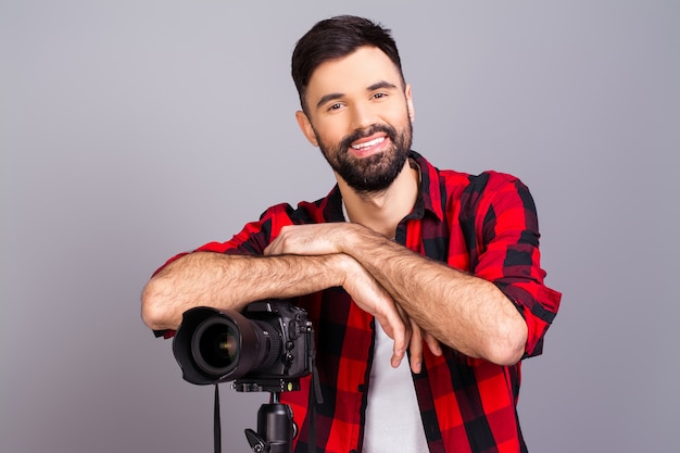 Enthousiaste heureux jeune homme debout avec caméra en studio