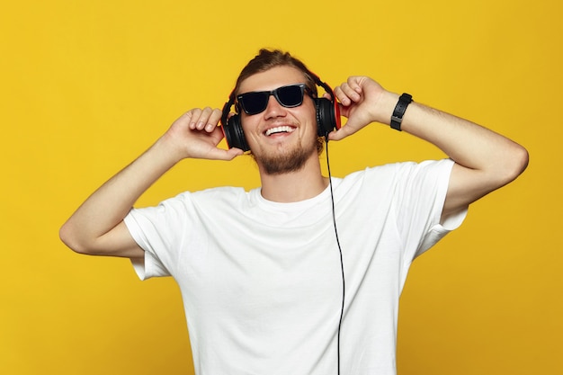 Enthousiaste homme caucasien avec des lunettes de soleil, écouter de la musique avec des écouteurs