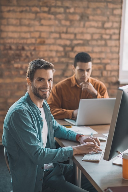 Enthousiaste homme intelligent assis devant son ordinateur tout en étant au travail