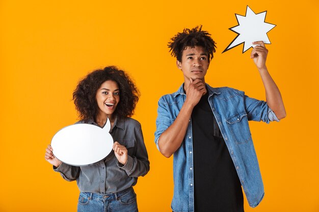 Photo enthousiaste jeune couple africain debout isolé, tenant des bulles vides