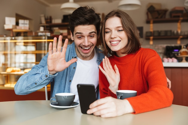 Enthousiaste jeune couple assis à une table de café ensemble