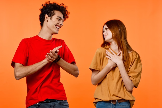 Enthousiaste jeune couple lifestyle studio fond orange vue recadrée