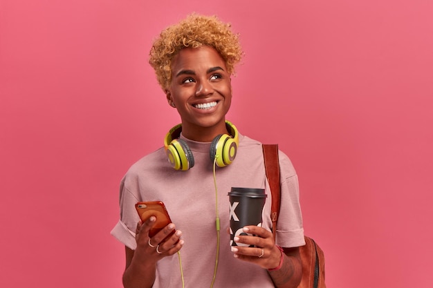 Enthousiaste jeune étudiant afro-américain souriant tenant un café à emporter