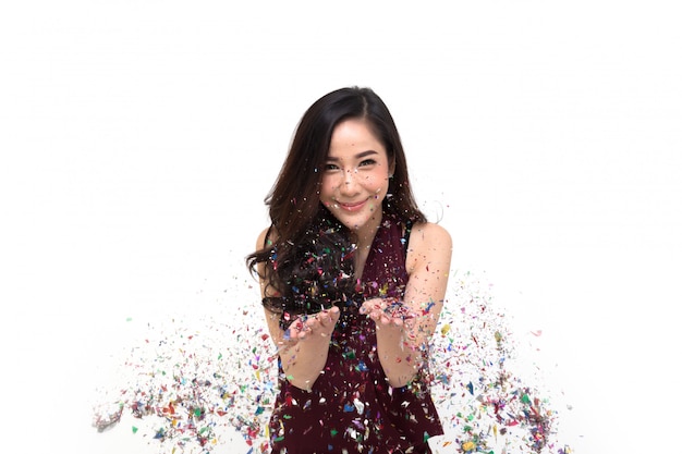 Enthousiaste jeune femme asiatique célébrant avec des confettis colorés isolé, modèle thaïlandais