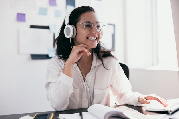 Enthousiaste jeune femme au casque appréciant écouter de la musique et souriant