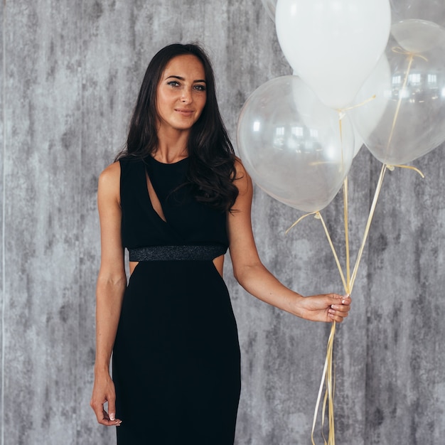 Enthousiaste jeune femme avec des ballons debout et souriant.