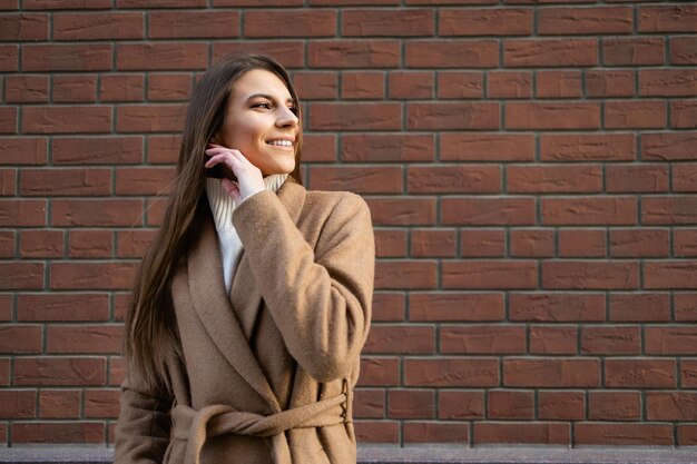 Enthousiaste jeune femme sur fond de mur de briques