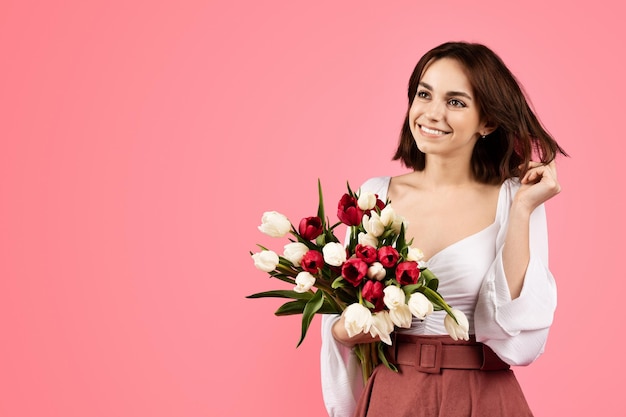 Enthousiaste jeune femme de race blanche avec bouquet de fleurs profiter du temps libre et anniversaire regarder l'espace libre