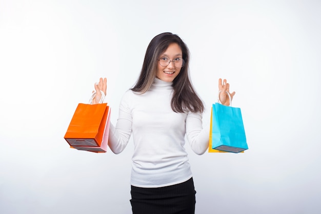 Enthousiaste jeune femme tient des sacs à provisions sur blanc.