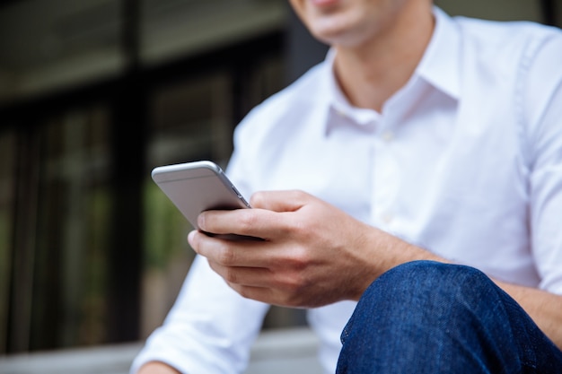 Enthousiaste jeune homme d'affaires à l'aide de smartphone près du centre d'affaires