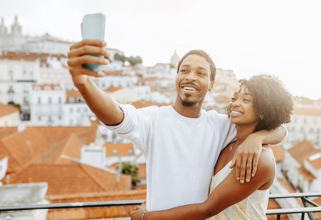 Enthousiaste jeune homme afro-américain étreignant une dame en robe prendre une photo de selfie pour les réseaux sociaux