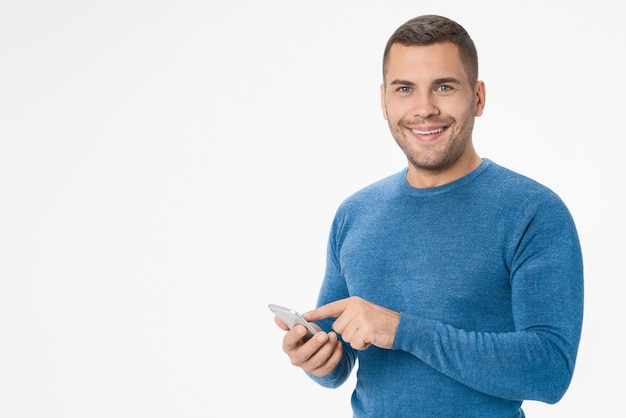 Enthousiaste jeune homme à l'aide de téléphone mobile isolé sur fond blanc