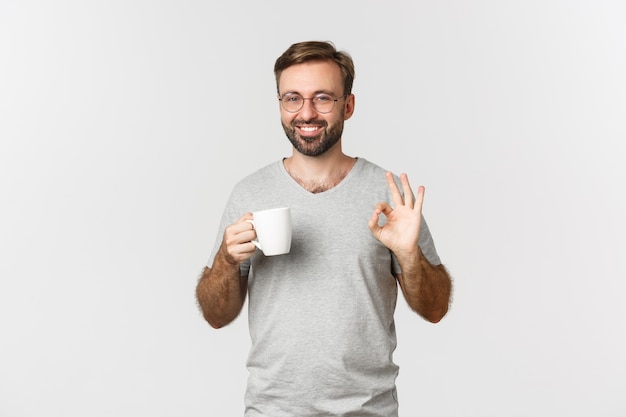 Enthousiaste jeune homme avec barbe, portant des lunettes et un t-shirt gris