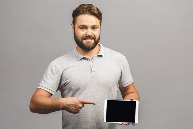 Enthousiaste jeune homme barbu en pointant occasionnel sur tablette écran blanc