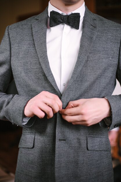 Enthousiaste jeune homme dans un costume gris touche une veste