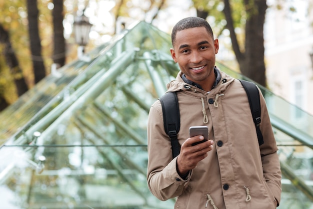 Enthousiaste jeune homme tenant son téléphone dans les mains et regardant à l'avant