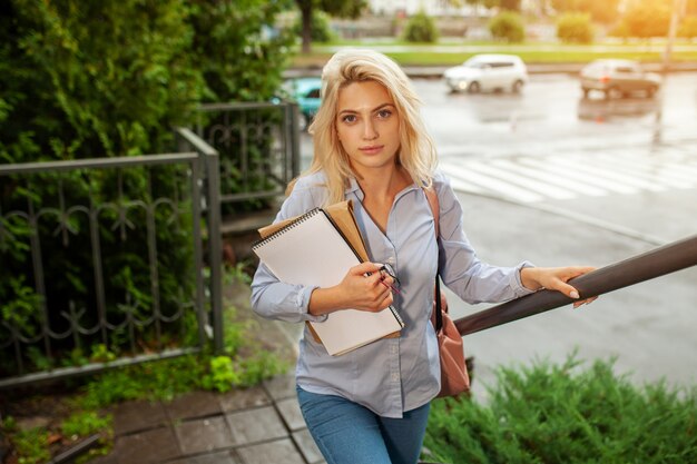 Enthousiaste Sérieux belle jeune fille tenant une pile de livres