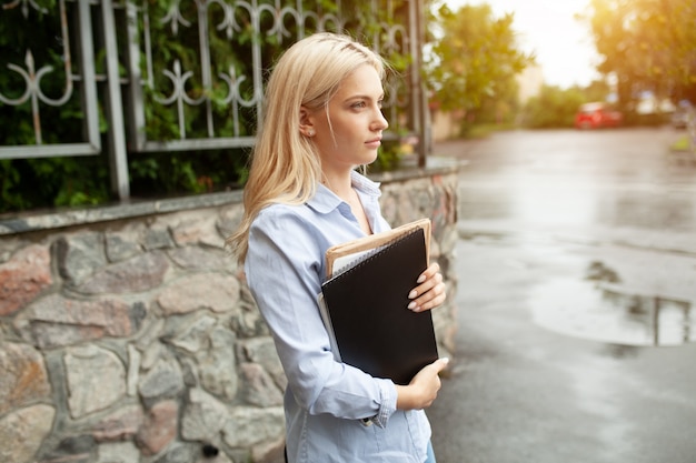 Enthousiaste Sérieux belle jeune fille tenant une pile de livres