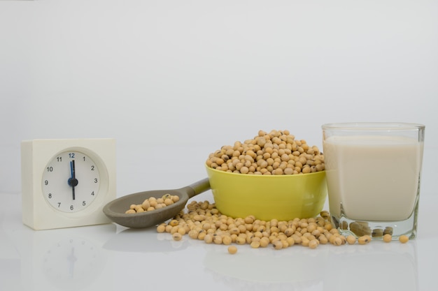 Entièrement des graines de soja dans le bol, du lait de soja et une cuillère pour la pause du matin sur une table blanche.