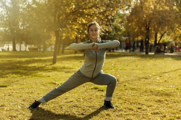 Entraînement d'aérobic à l'extérieur. Jeune femme sportive en vêtements de sport s'entraîne dans le parc en automne.