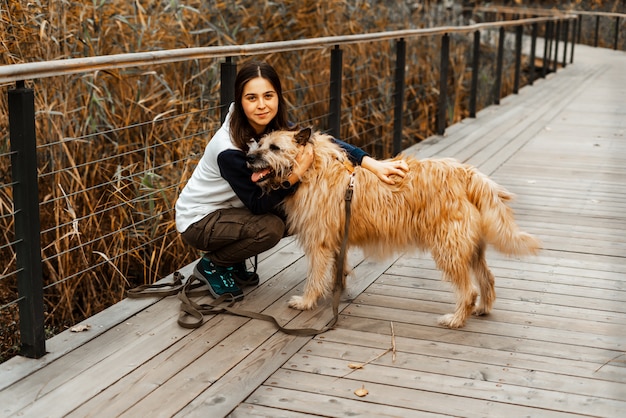 Entraînement des animaux. Une fille bénévole marche avec un chien dans un refuge pour animaux. Fille avec un chien dans le parc en automne