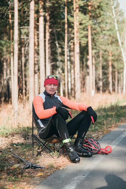 Entraînement d'un athlète sur les patins à roulettes Balade en biathlon sur les skis à roulettes avec des bâtons de ski dans le casque Entraînement d'automne Sport à roulettes Homme adulte à cheval sur des patins L'athlète se prépare à commencer