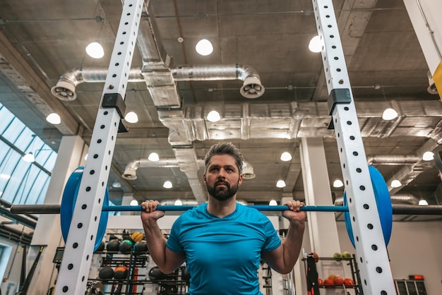 Entraînement à la barre. Athlète semblant déterminé et sérieux tout en travaillant avec une barre