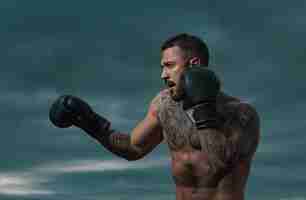 Photo entraînement de boxeur combattant en plein air sportiste de muay thai boxeur se battant dans des gants homme sportif pendant les exercices de boxe attaque de force et concept de mouvement entraînements de boxe en plein air corps de l'homme musculaire