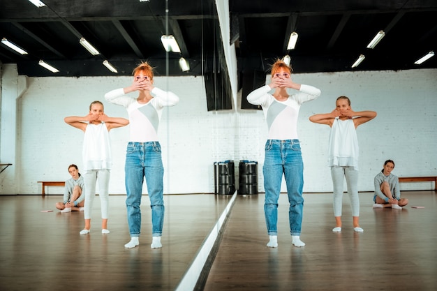 Entraînement de danse. Professeur de ballet aux cheveux roux et ses élèves se sentent concentrés tout en pratiquant des éléments de la danse moderne