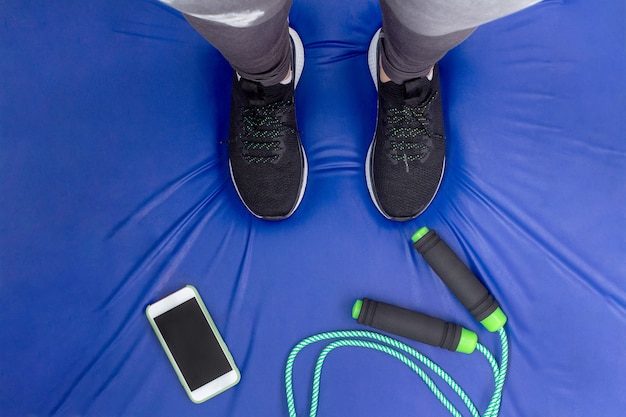 Entraînement à domicile Corde et téléphone portable sur le côté sur un tapis bleu