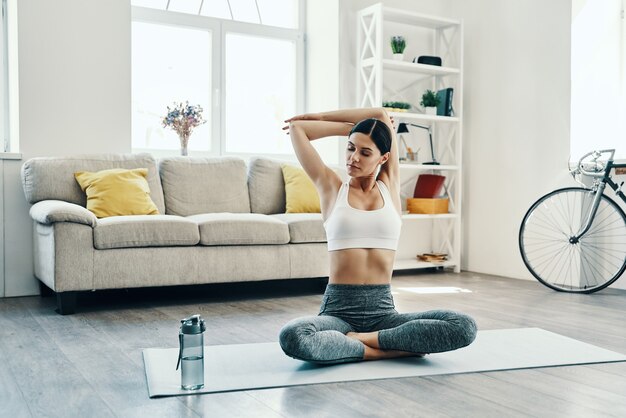 Entraînement du matin. Belle jeune femme en vêtements de sport pratiquant le yoga tout en passant du temps à la maison