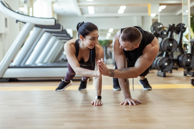 Entraînement ensemble Homme et femme sportifs s'entraînent en faisant des pompes et en donnant cinq dans la salle de sport Style de vie sain