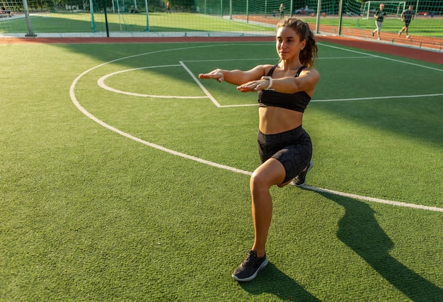 Entraînement extérieur. Un modèle de fitness sexy et attrayant se réchauffe et étire les muscles avant l'entraînement