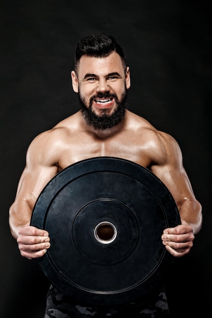 Entraînement d'homme musclé avec un poids de plaque d'haltères lourd