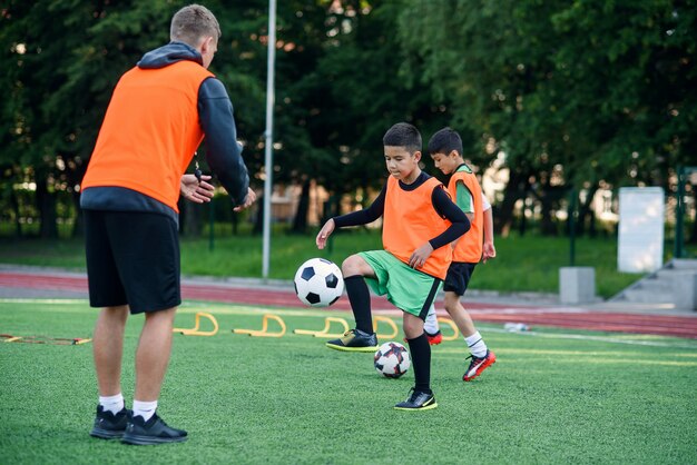 Deux écoliers Exécutent Des Exercices D'échelle Sur Le Gazon Pendant Le  Camp D'été De Football. Entraînement De Football Intense Avec L'entraîneur.