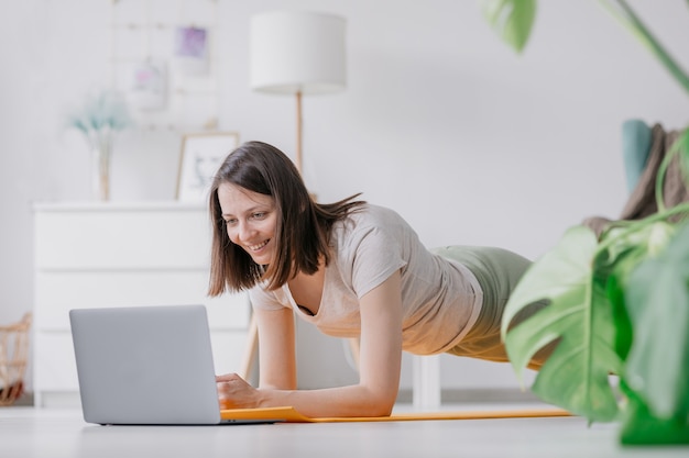 Entraînement à la méditation et au yoga à la maison femme faisant des exercices physiques avec un ordinateur portable