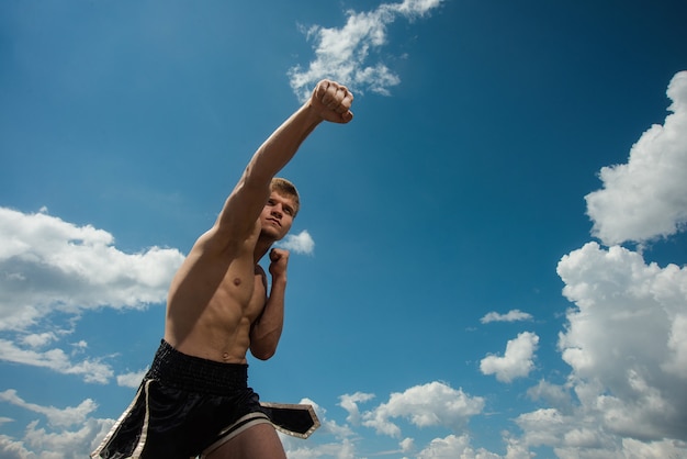 Entraînement musculaire de combattant masculin. Boxer s'entraîne en plein air