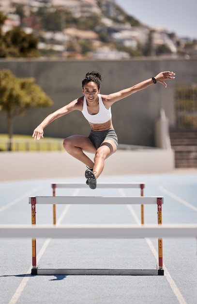 Entraînement physique et femme sautant des haies pour l'exercice sportif et cardio intense sur une piste de course