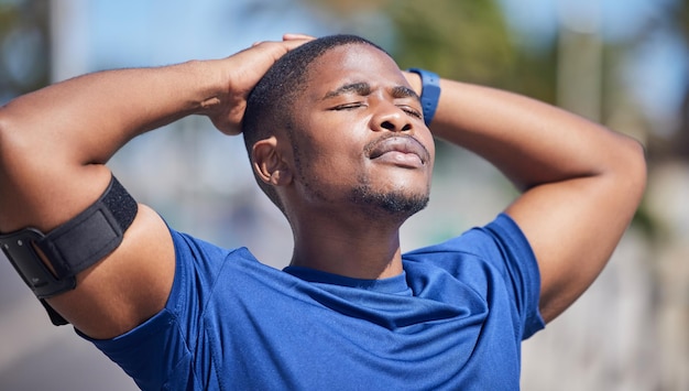 Entraînement de remise en forme et coureur d'homme noir fatigué avec le soleil sur le visage pour faire une pause après l'exercice cardio ou la course Entraînement s'arrêter et respirer par un homme athlétique se détendre à l'extérieur pour une course de marathon ou une routine sportive