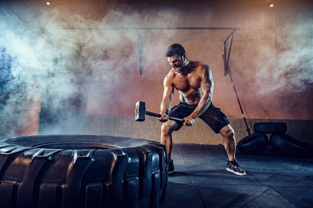 Entraînement sportif pour l'endurance, l'homme frappe un gros marteau de pneu. Entraînement de concept.