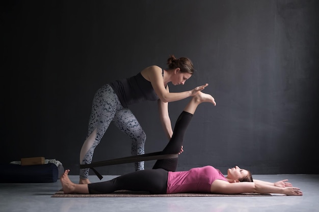 Entraîneur Aidant Une Fille à Faire La Main Allongée Au Gros Orteil Pose Supta Padangusthasana