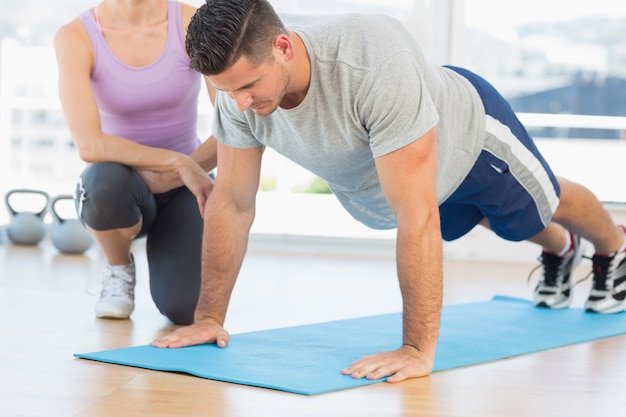 Entraîneur aidant l&#39;homme avec des push-ups