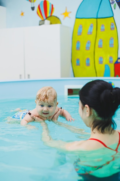 L'entraîneur apprend au bébé à nager dans la piscine pour enfants Développement de l'enfant