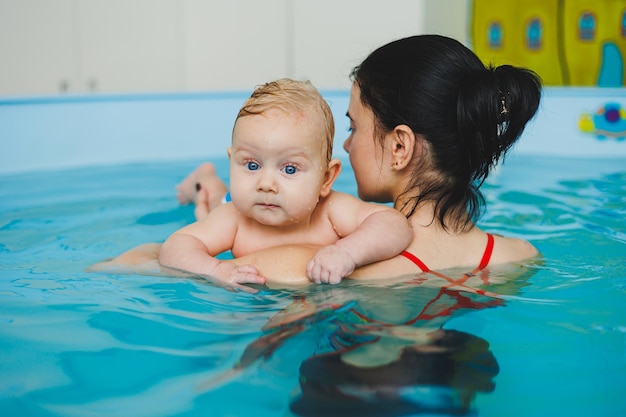 L'entraîneur apprend au bébé à nager dans la piscine pour enfants Développement de l'enfant