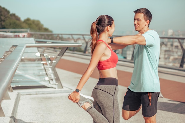 Entraîneur et athlète réchauffant les jambes avant l'entraînement à l'extérieur le matin