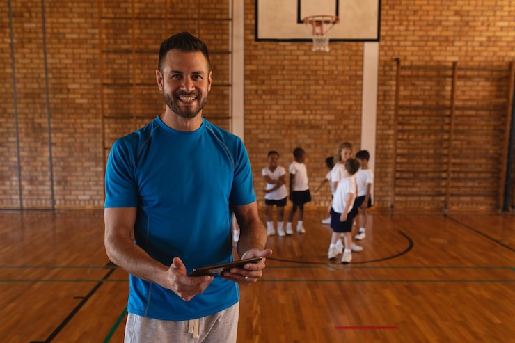 Photo un entraîneur de basket-ball heureux en utilisant une tablette numérique sur le terrain de basket à l'école