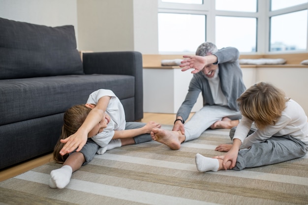 Entraîneur à domicile. Père entraînant ses enfants à la maison en les faisant s'étirer correctement