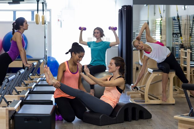 Entraîneur féminin aidant femme avec exercice d'étirement sur arc baril